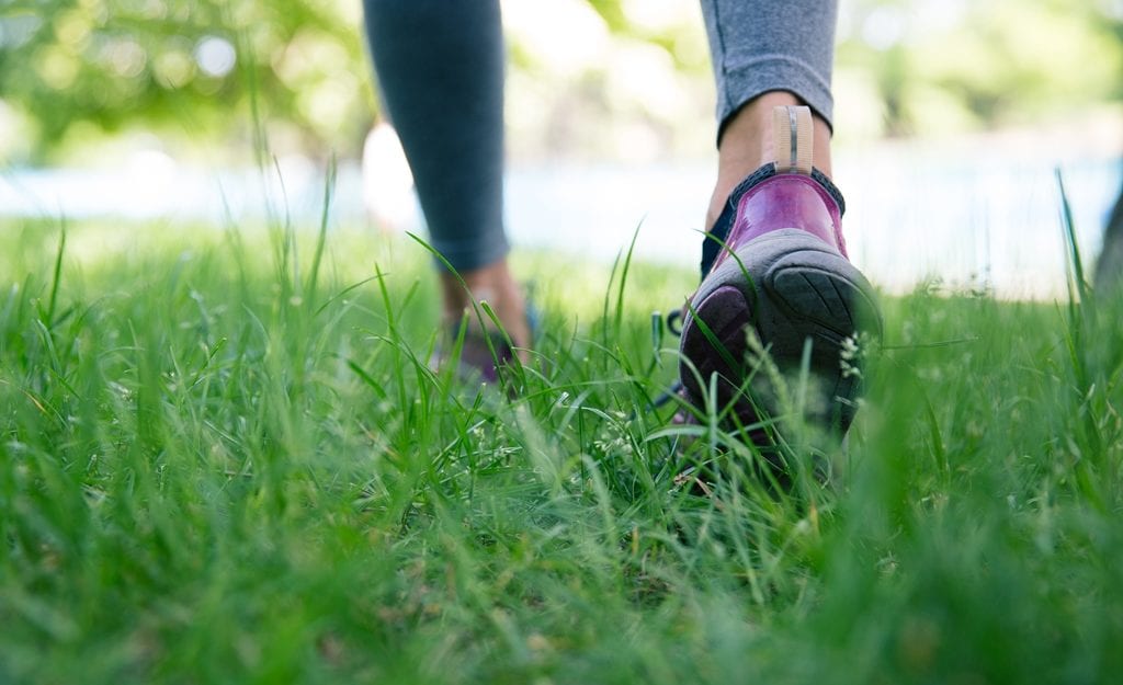 Footwear on female feet running on green grass