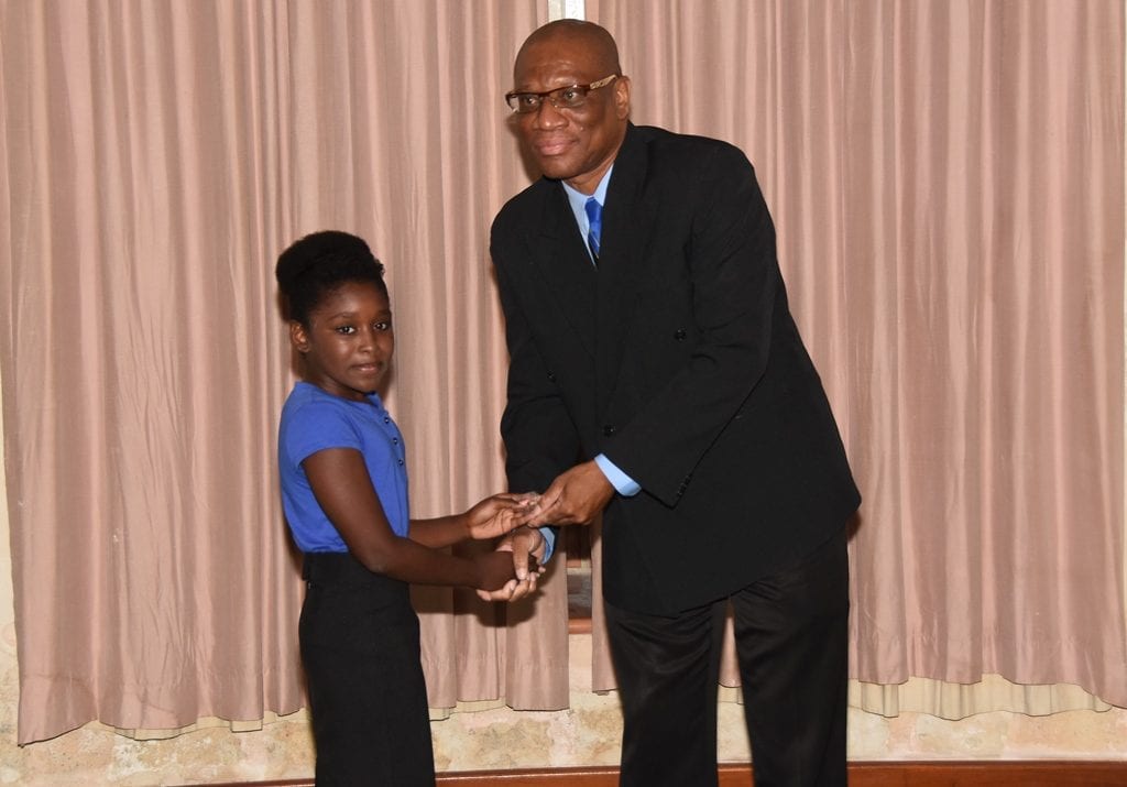 Director of Youth, Cleviston Hunte presenting Ashley Alkins with a pin during the installation ceremony of the 2016 Youth Parliamentarians in the House of Assembly today. (C.Pitt/BGIS)